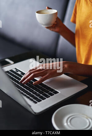 Donna di mano digitando su laptop in cafe Foto Stock