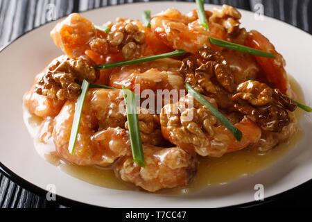 Gamberi croccanti si lancia in una cremosa salsa dolce e canditi di noci close-up su una piastra orizzontale. Foto Stock