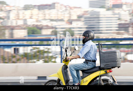 Belgrado, Serbia - Aprile 26, 2019: uomo maturo in sella al suo scooter retrò sulla strada di città ponte con sfocata luminosa cityscape sfondo Foto Stock