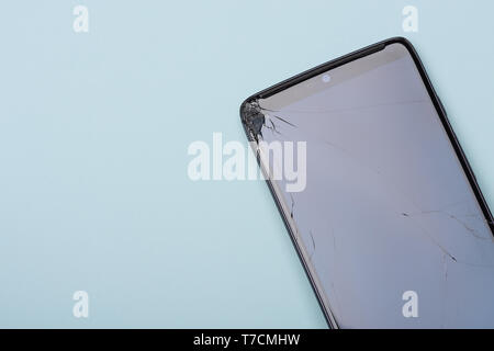 Smartphone con vetro rotto telefono dello schermo touchscreen su sfondo blu. Vista da sopra con copia spazio. Foto Stock