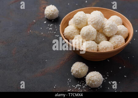 Caramelle in scaglie di cocco ciotola sul scuro dello sfondo della tabella Foto Stock