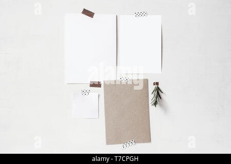 Set di biglietti vuoti, nota mockups di carta. Fogli vuoti di bianco e carta kraft e il rosmarino e il ramo di erbe nastrato sul vecchio muro bianco. Design mo Foto Stock