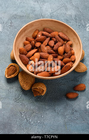 Salate mandorle fritte in una ciotola con mandorle noci in gusci Foto Stock