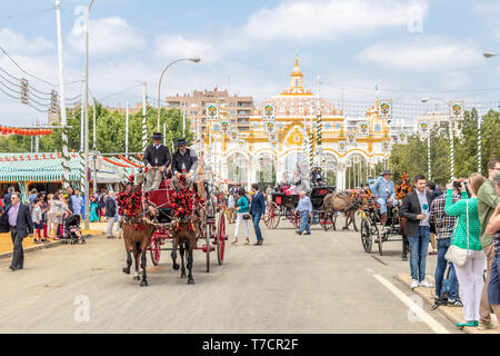 Siviglia, Spagna - 5 Maggio 2019: le persone che entrano in carrozza trainata da cavalli per la fiera di aprile dalla porta principale della fiera di Siviglia il Maggio 5, 2019 a Siviglia Foto Stock