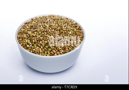 Verde semi di grano saraceno isolati su sfondo bianco, ceramica ciotola piena di materie verde chicchi di grano saraceno Foto Stock