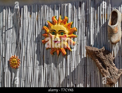 Giardino pensile ornamenti costituito da 2 ceramica dipinta Suns, alcuni sughero naturale e un vecchio in legno pitturato intasare olandese in Andalusia in Spagna. Foto Stock