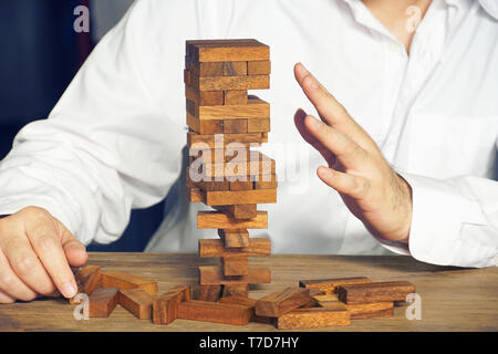 Imprenditore che agisce per smettere di distruggere dal blocco di legno di costruzione,il concetto di rischio. Foto Stock