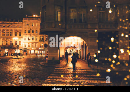 Repubblica Ceca, Praga - Dicembre 24, 2018: strada notte in una città europea con bokeh da lanterne di Natale, sagome di persone e facciate di b Foto Stock