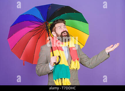 Un ombrello è necessario in un giorno di pioggia. O autistico di rain man holding ombrello coloratissimo. L'autismo. Uomo Barbuto controllare se piove. Moda Uomo con accessori colorati. Lasciare la pioggia. Foto Stock