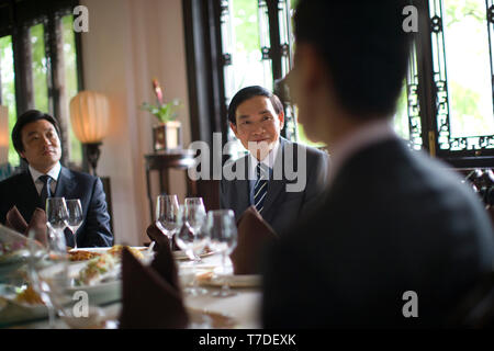 Due imprenditori seduti attorno a un tavolo da pranzo con i colleghi. Foto Stock