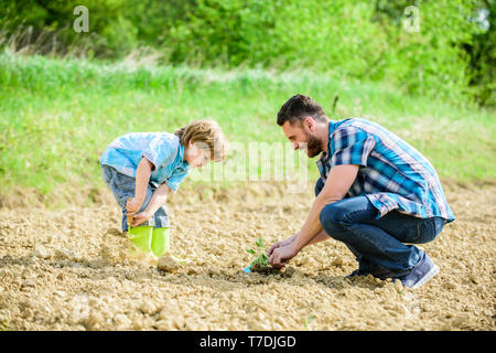 Felice giornata della terra. Albero di famiglia. ricco terreno naturale. Eco farm. piccolo bambino aiutare il padre in agricoltura. nuova vita. Progettazione ecologica. padre e figlio piantare fiori nel suolo. La giornata della terra. Foto Stock