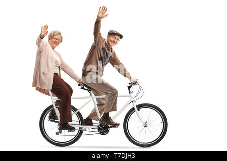 A piena lunghezza shot di una coppia Senior in sella ad una bici in tandem e agitando isolati su sfondo bianco Foto Stock