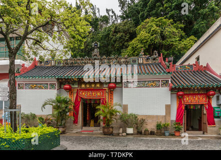 Hong Kong, Cina - 7 Marzo 2019: Tai O villaggio di pescatori. Vista frontale di Kwan Tai tempio taoista con muro bianco e rosso ai portali. Ampie decorazioni del tetto Foto Stock