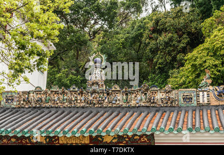 Hong Kong, Cina - 7 Marzo 2019: Tai O villaggio di pescatori. Ampia statua decorazioni sul tetto di Kwan Tai tempio taoista. Circondato dal verde fogliame. Foto Stock