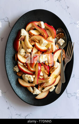 Insalata di pere con vena blu formaggio, noci e un condimento piccante su un nero piatto di servizio. Foto Stock