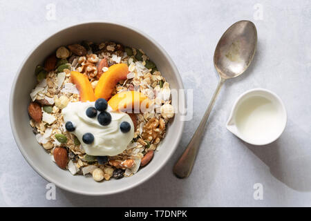 Ciotola di cereali integrali cereali per la prima colazione con un cucchiaio e la brocca del latte. Foto Stock