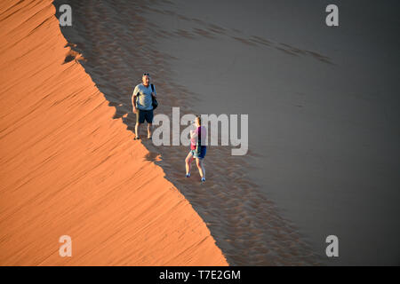 I turisti fotografare sé arrampicata su una cresta in Sossusvlei, presa su 01.03.2019. Il Sossusvlei nel Namib-Naukluft National Park è stato un Sito Patrimonio Mondiale dell'UNESCO dal 2013, e il suo famoso, quasi 400 metri di alta duna è uno dei più alti del mondo. In basso la precipitazione area di dune, che è uno dei particolari attrazioni turistiche della Namibia, diventa molto caldo durante i mesi estivi. L'arancio-rosso della sabbia è causata da una elevata proporzione di ossido di ferro. Foto: Matthias Toedt/dpa-Zentralbild/ZB/Picture Alliance | Utilizzo di tutto il mondo Foto Stock