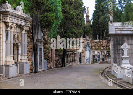 Vista prospettica del sentiero curvo con tombe e cripte sul Montjuic cimitero nel giorno nuvoloso, Barcellona, in Catalogna, Spagna Foto Stock