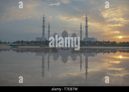 Vista assiale della Grande Moschea di Abu Dhabi al tramonto con la riflessione su uno specchio di acqua con nessuno, Regno emirato Arabo Foto Stock