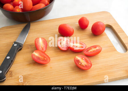 Affettare il pomodoro Uva su un tagliere Foto Stock