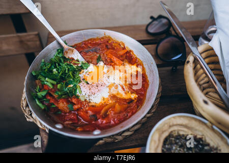 Shakshuka, uova fritte in salsa di pomodoro sulla tavola. Street Restaurant Foto Stock