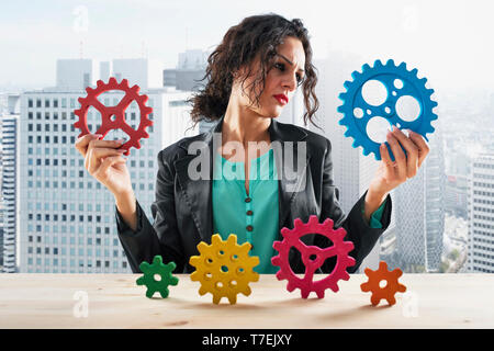 Imprenditrice tenta di lavorare con gli ingranaggi. Concetto di partnership e il lavoro di squadra Foto Stock