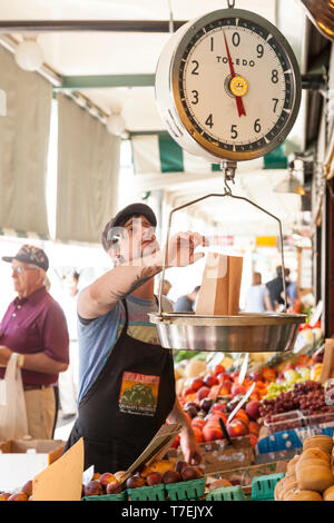 Uomo di pesatura fornitore di produrre con una scala a Pike Place Market, Seattle, Washington, Stati Uniti. Per solo uso editoriale. Foto Stock