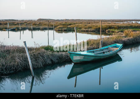 Weathered e abbandonata piccola barca vicino alla riva in tranquilla laguna sul luminoso giorno. Foto Stock