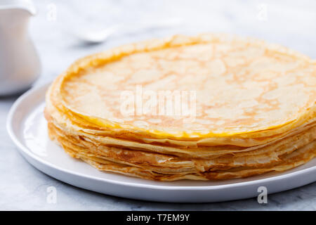 Crepes, sottile frittelle con miele su una piastra bianca. Close up. Foto Stock