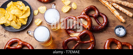 La birra, salati salatini, patatine, formaggio bastoni sullo sfondo di legno. Vista dall'alto. Foto Stock