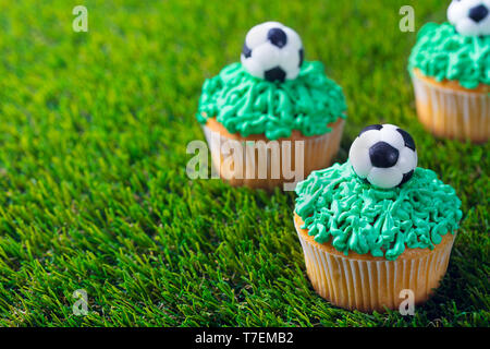 Festa del calcio, compleanno decorata cupcake su erba verde dello sfondo. Copia dello spazio. Foto Stock