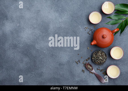 Il tè verde nella teiera e chawan bocce, tazze sullo sfondo di ardesia. Vista dall'alto. Copia dello spazio. Foto Stock