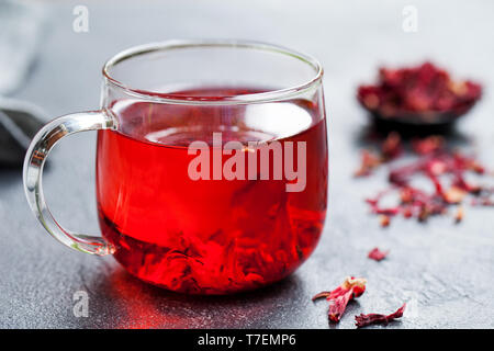 Hibiscus tè in tazza di vetro. Sfondo grigio. Close up. Foto Stock