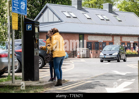 Madre e figlia utilizzando una retribuzione e display del misuratore di parcheggio in un parcheggio Foto Stock