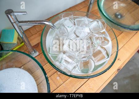 Un sacco di un bicchiere di vetro di acqua nel lavandino di vetro pronto per lavare e pulire. Foto Stock