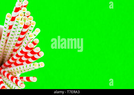 Paillette rosso per il succo in un bicchiere di carta su uno sfondo verde. Foto Stock