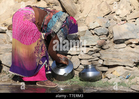 Donna portare acqua pesante ciotola sulla testa un'lungo la strada per la loro casa Foto Stock