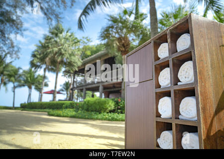 Asciugamano di rotolamento in legno scatola quadrata nella spiaggia privata dell'hotel garden, preparato per traveler per l'uso. Foto Stock