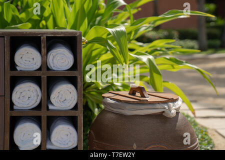 Asciugamano di rotolamento in legno scatola quadrata nella spiaggia privata dell'hotel garden, preparato per traveler per l'uso. Foto Stock