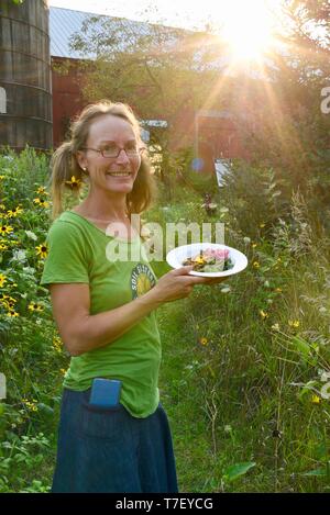 Donna agricoltore chef catering sul lavoro del suo allevamento di suini, con un pasto preparato realizzato con il patrimonio di suini che ha sollevato, Farm Cena, Blanchardville, WI, Stati Uniti d'America Foto Stock