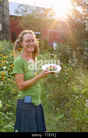 Donna agricoltore chef catering sul lavoro del suo allevamento di suini, con un pasto preparato realizzato con il patrimonio di suini che ha sollevato, Farm Cena, Blanchardville, WI, Stati Uniti d'America Foto Stock