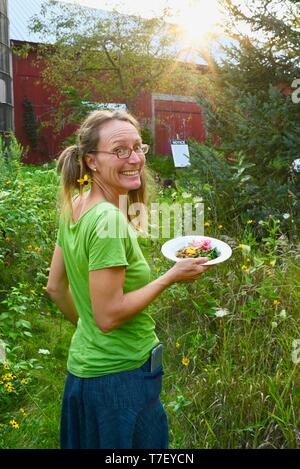 Donna agricoltore chef catering sul lavoro del suo allevamento di suini, con un pasto preparato realizzato con il patrimonio di suini che ha sollevato, Farm Cena, Blanchardville, WI, Stati Uniti d'America Foto Stock
