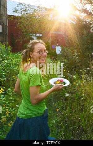 Donna agricoltore chef catering sul lavoro del suo allevamento di suini, con un pasto preparato realizzato con il patrimonio di suini che ha sollevato, Farm Cena, Blanchardville, WI, Stati Uniti d'America Foto Stock