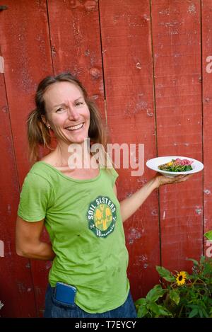 Donna agricoltore chef catering sul lavoro del suo allevamento di suini, con un pasto preparato realizzato con il patrimonio di suini che ha sollevato, Farm Cena, Blanchardville, WI, Stati Uniti d'America Foto Stock