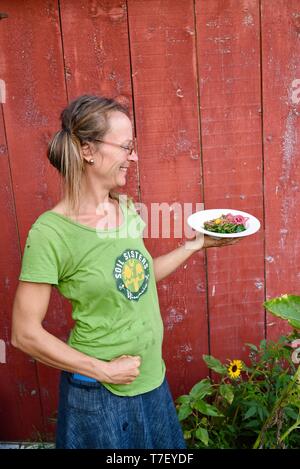 Donna agricoltore chef catering sul lavoro del suo allevamento di suini, con un pasto preparato realizzato con il patrimonio di suini che ha sollevato, Farm Cena, Blanchardville, WI, Stati Uniti d'America Foto Stock