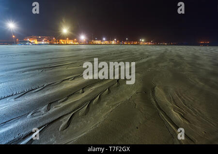 Sfuggente di acqua a bassa marea con linee di trama nella sabbia e la sera che riflette la luce del sole lungo i bordi. Il Marocco Foto Stock