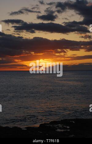 Tramonto sul mare in Oahu Hawaii, Hawaiian isola arancione tramonto cielo incandescente con nuvole di orientamento verticale Foto Stock