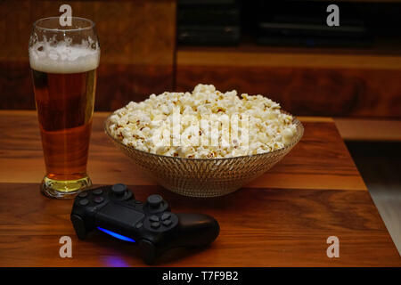 La pinta di birra ciotola di popcorn e gamepad su sfondo di legno home entertainment Foto Stock