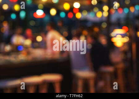 Sfocare lo sfondo della gente seduta al ristorante, bar o night club con luci colorate bokeh di fondo. Foto Stock