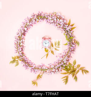Telaio a cerchio di rosa sveglia e bellissimi fiori di glicine ramo con boccioli di fiori su sfondo rosa. Foto Stock